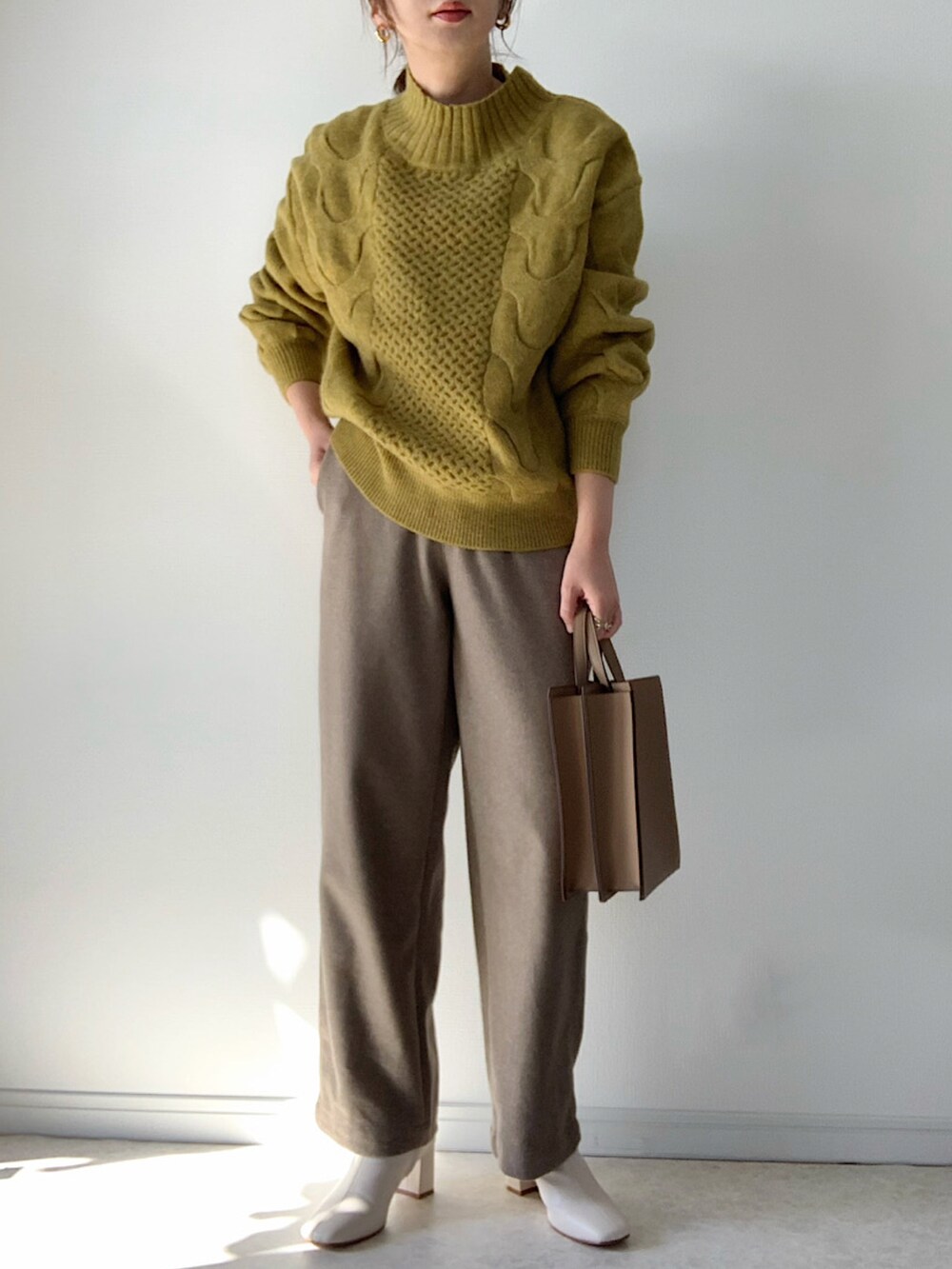 イエロー系のニット/セーター、ブラック系のデニムパンツ、その他のエコバッグ/サブバッグを着用したレディースの冬コーディネートの2枚目の写真