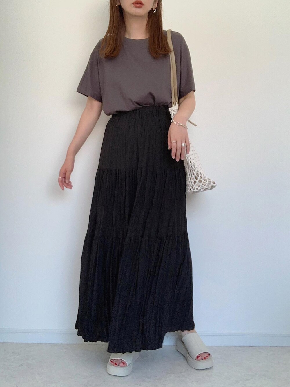 ベージュ系のTシャツ/カットソー、ブラック系のスカート、ホワイト系のサンダルを着用したレディースの夏コーディネートの3枚目の写真