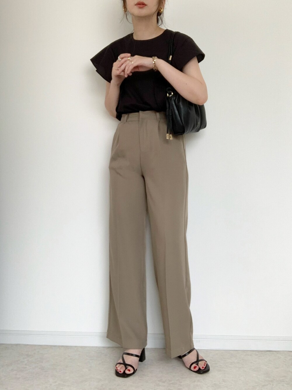 ベージュ系のTシャツ/カットソー、ブラウン系のスラックス、ベージュ系のサンダルを着用したレディースの夏コーディネートの2枚目の写真