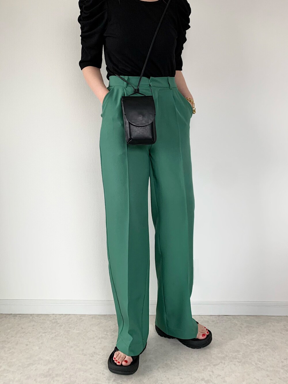 ブラック系のTシャツ/カットソー、グリーン系のスラックス、ブラック系のサンダルを着用したレディースの春コーディネートの2枚目の写真