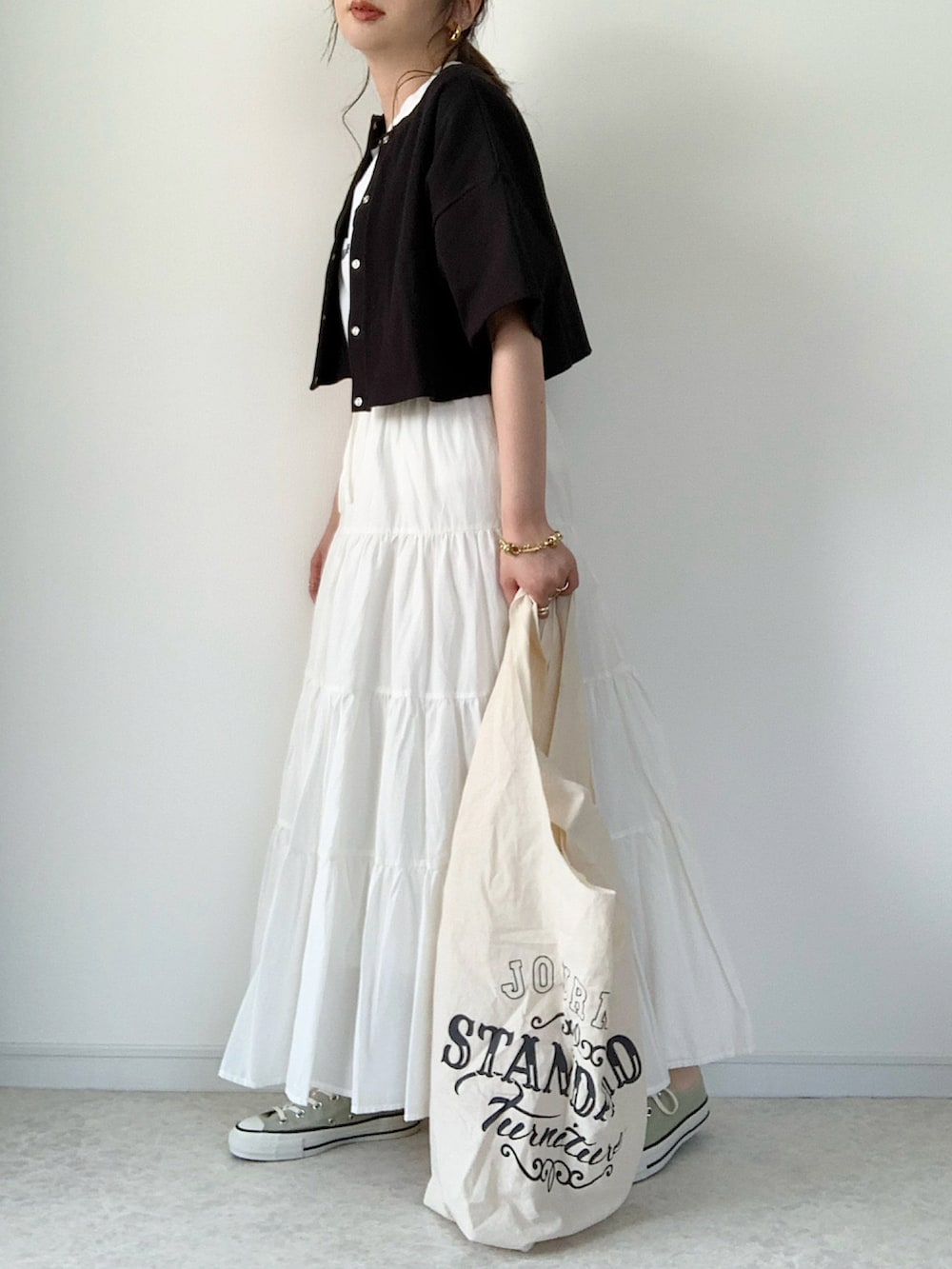 ブラック系のTシャツ/カットソー、ホワイト系のスカート、ブラック系のサンダルを着用したレディースの春コーディネートの5枚目の写真