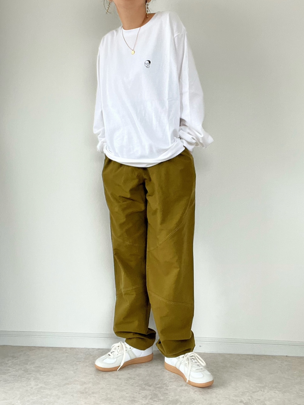 グリーン系のスラックス、ホワイト系のTシャツ/カットソーを着用したレディースの冬コーディネートの2枚目の写真