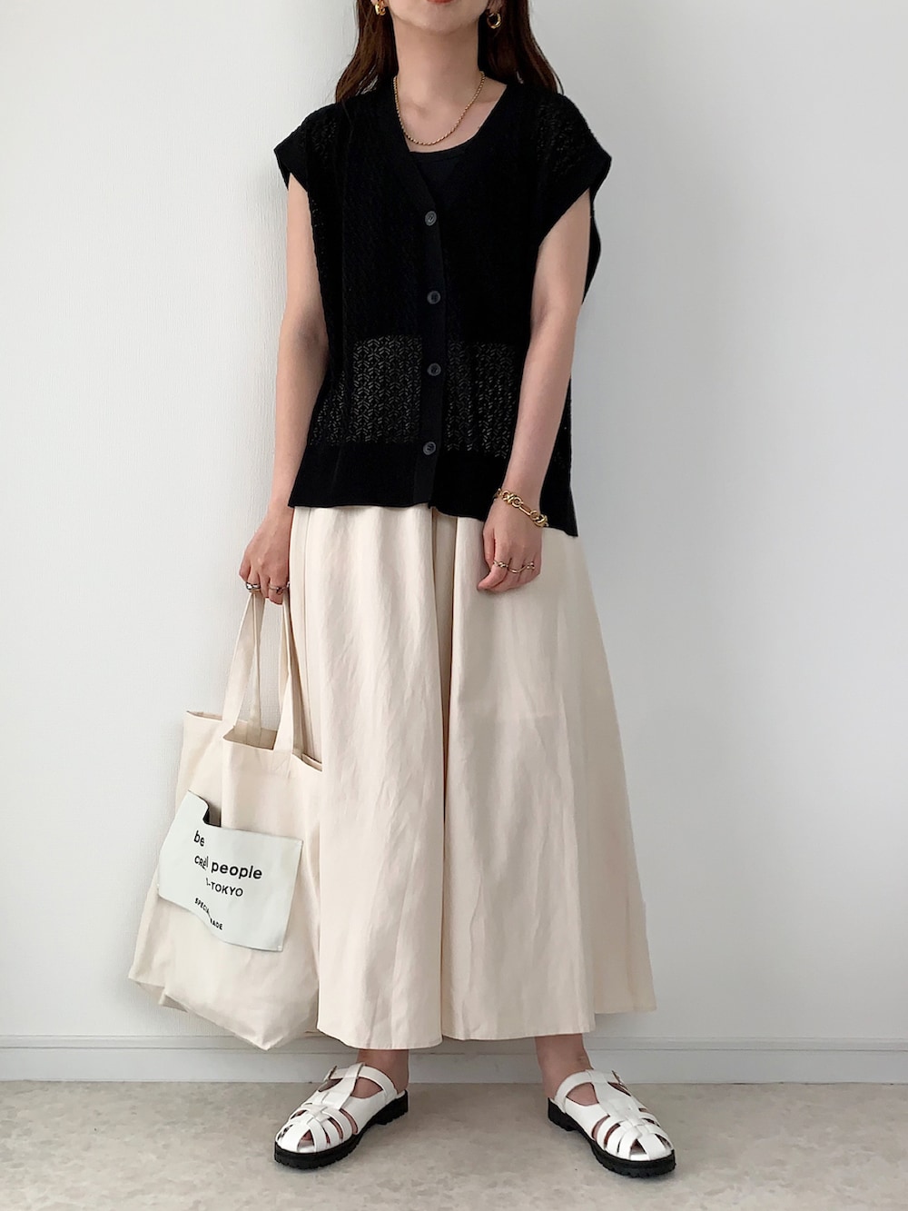 ブラック系のベスト、ベージュ系のその他パンツ、ホワイト系のサンダルを着用したレディースの夏コーディネートの2枚目の写真