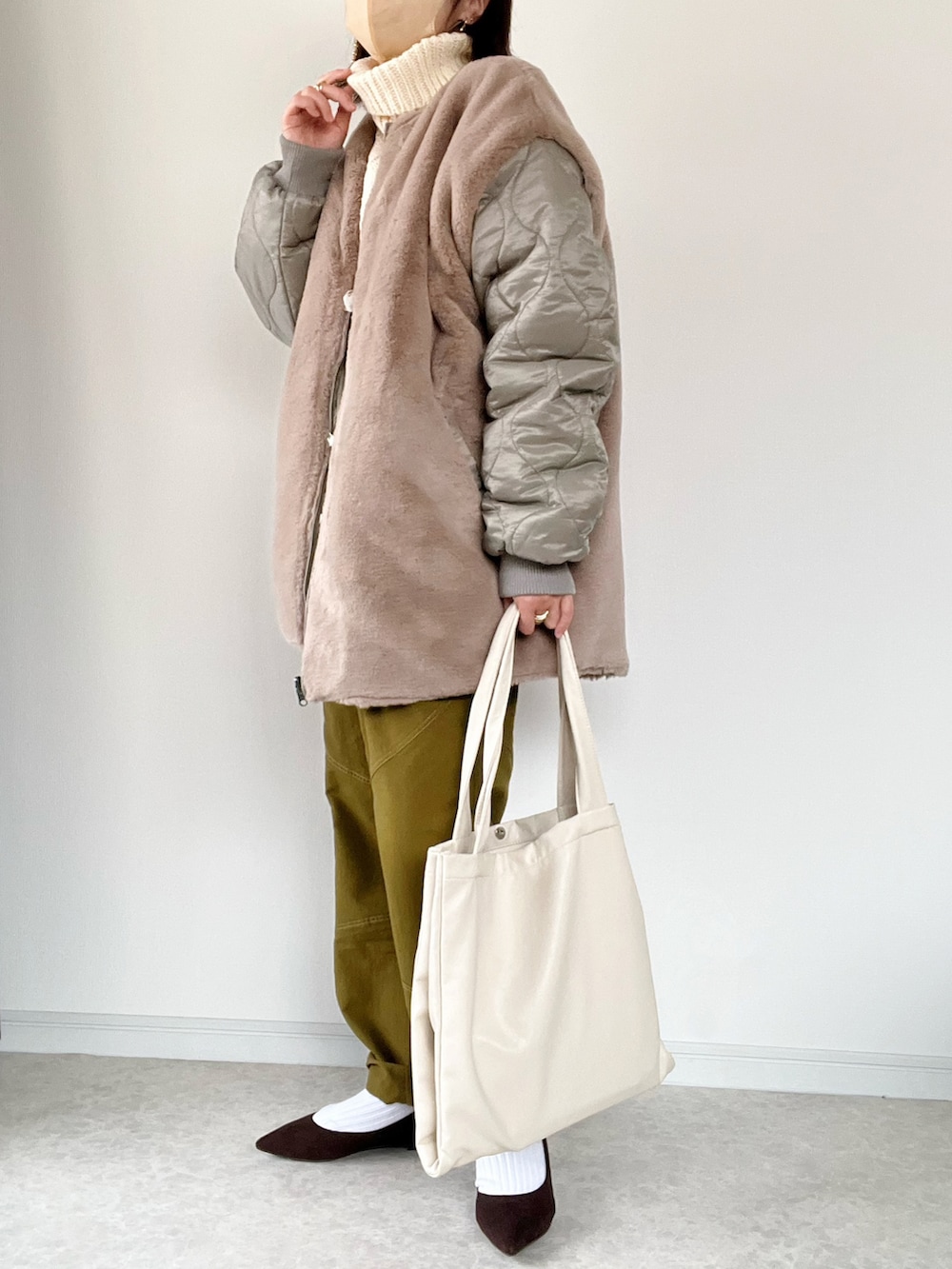 ホワイト系のニット/セーター、グリーン系のスラックス、ブラウン系のパンプスを着用したレディースの冬コーディネートの2枚目の写真