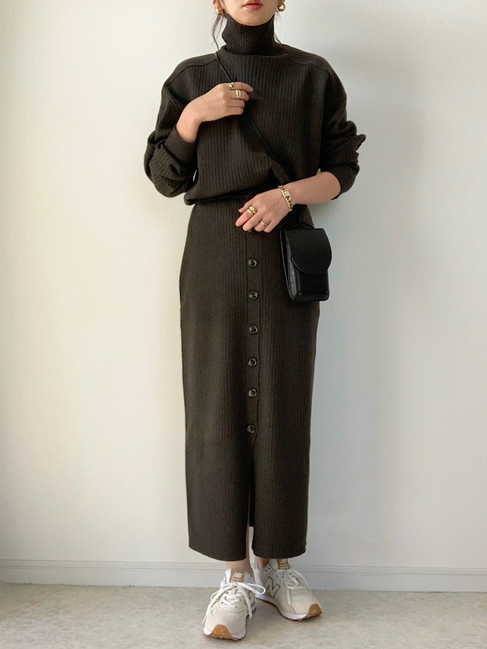 イエロー系のニット/セーター、グレー系のスカート、ホワイト系のブーツを着用したレディースの秋コーディネートの2枚目の写真