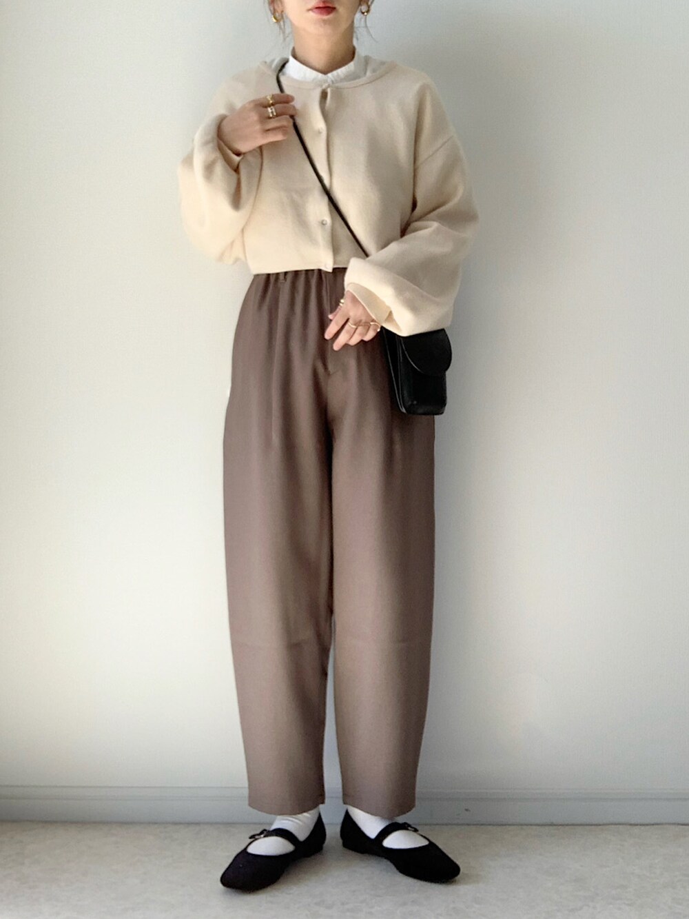 ブラウン系のチェスターコート、ブラウン系のパンツ、ホワイト系のカーディガン/ボレロを着用したレディースの秋コーディネートの2枚目の写真