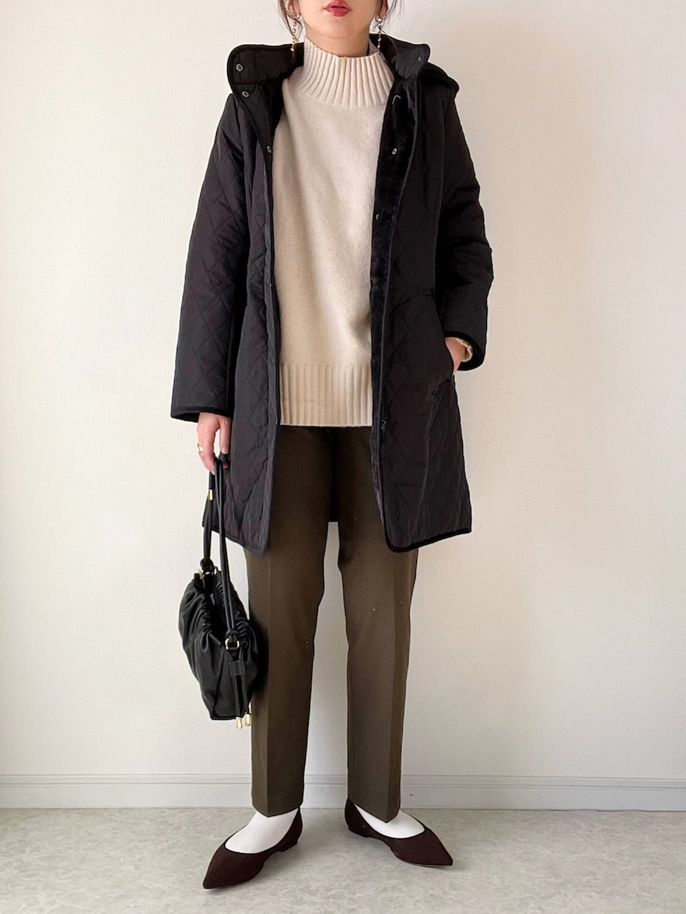 ブラック系のその他アウター、ホワイト系のTシャツ/カットソー、ホワイト系のハンドバッグを着用したレディースの冬コーディネートの3枚目の写真