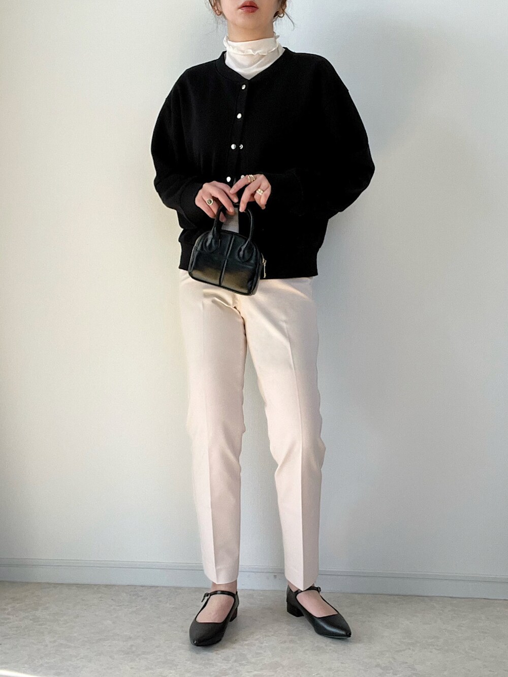 ブラック系のボストンバッグ、ブラック系のパンプス、ベージュ系のパンツを着用したレディースの冬コーディネートの2枚目の写真