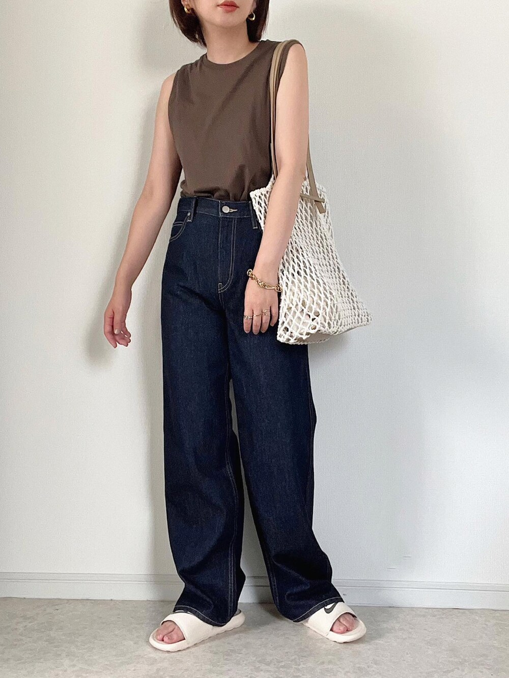 ベージュ系のベスト、ブルー系のデニムパンツ、ブラック系のショルダーバッグを着用したレディースの夏コーディネートの4枚目の写真