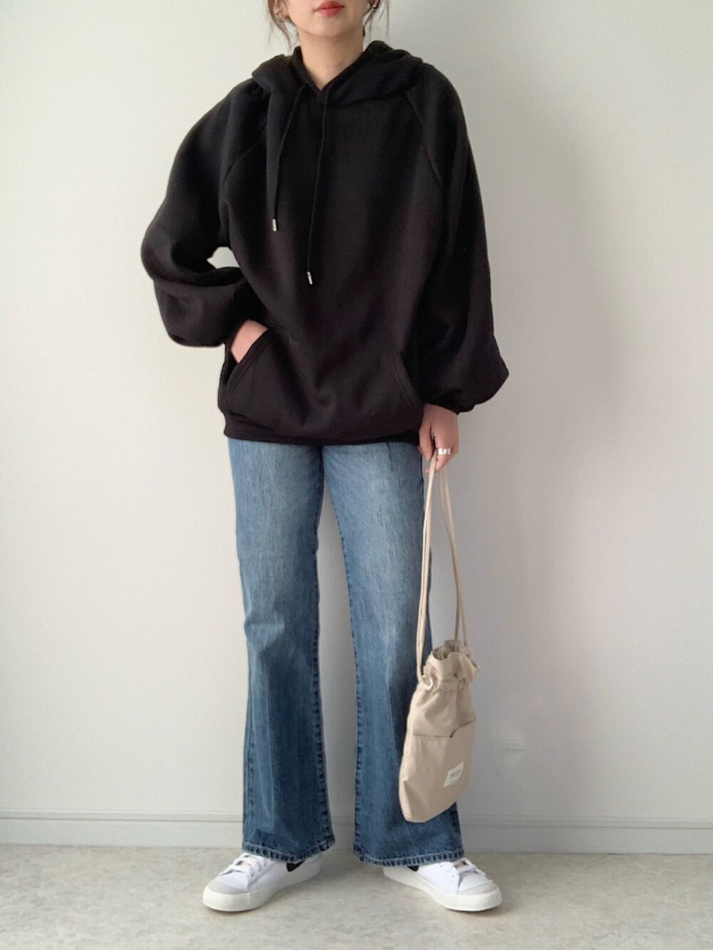 ブラック系のパーカー、ブルー系のデニムパンツ、ベージュ系のノーカラージャケットを着用したレディースの冬コーディネートの2枚目の写真