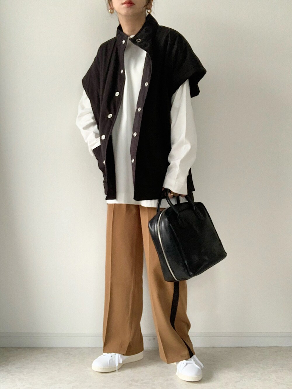 ブラック系のダウンベスト、イエロー系のその他パンツ、ホワイト系のスニーカーを着用したレディースの秋コーディネートの3枚目の写真