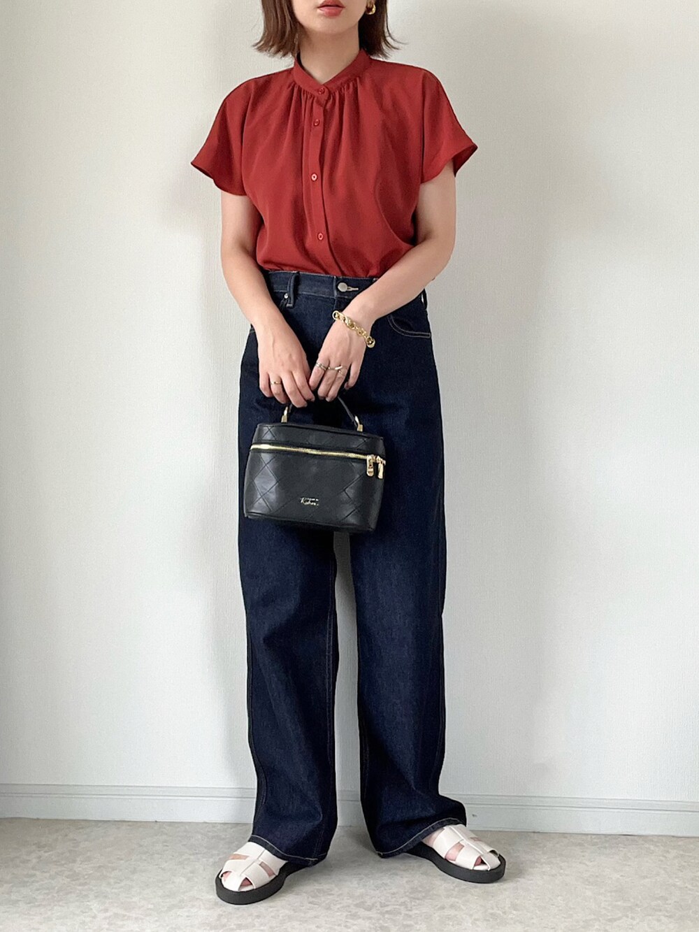 ベージュ系のベスト、ブルー系のデニムパンツ、ブラック系のショルダーバッグを着用したレディースの夏コーディネートの2枚目の写真