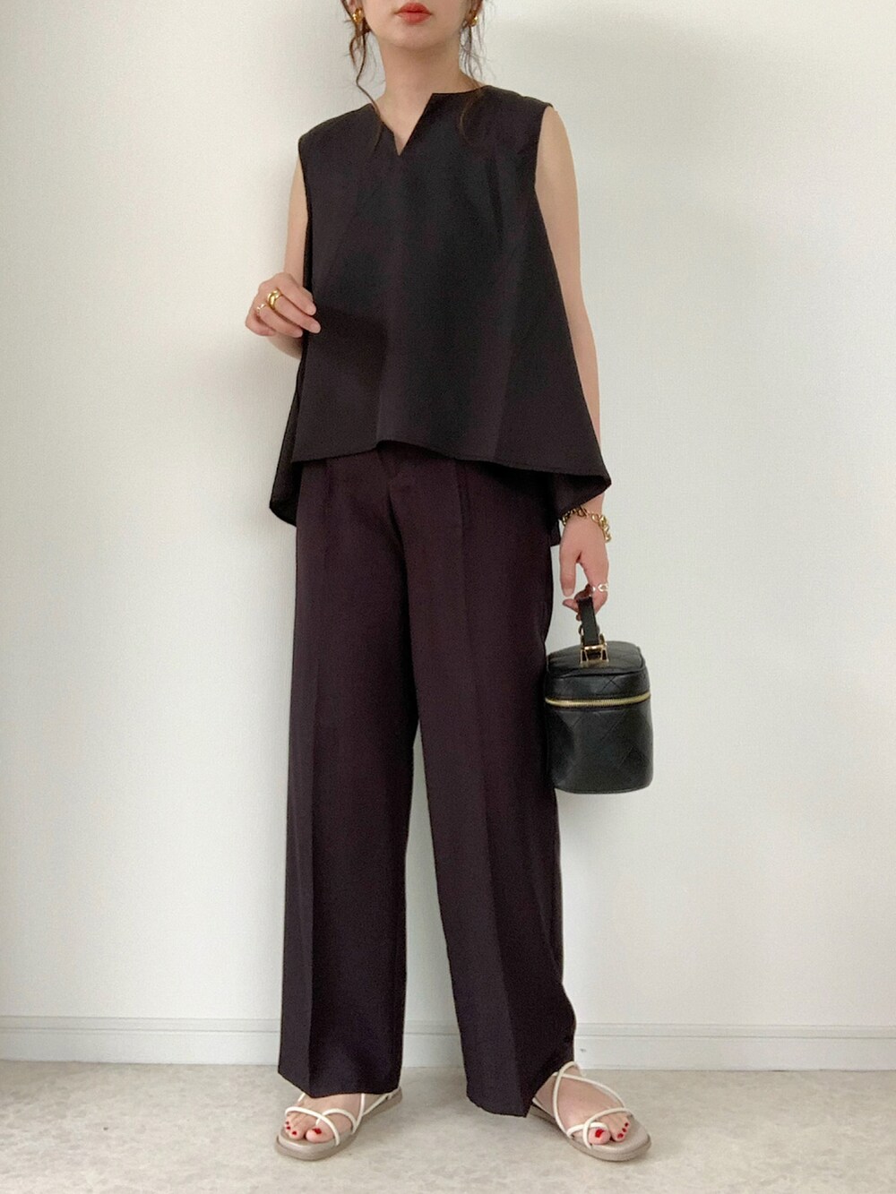 ブラック系のシャツ/ブラウス、ホワイト系のパンツ、ブラック系のサンダルを着用したレディースの夏コーディネートの2枚目の写真