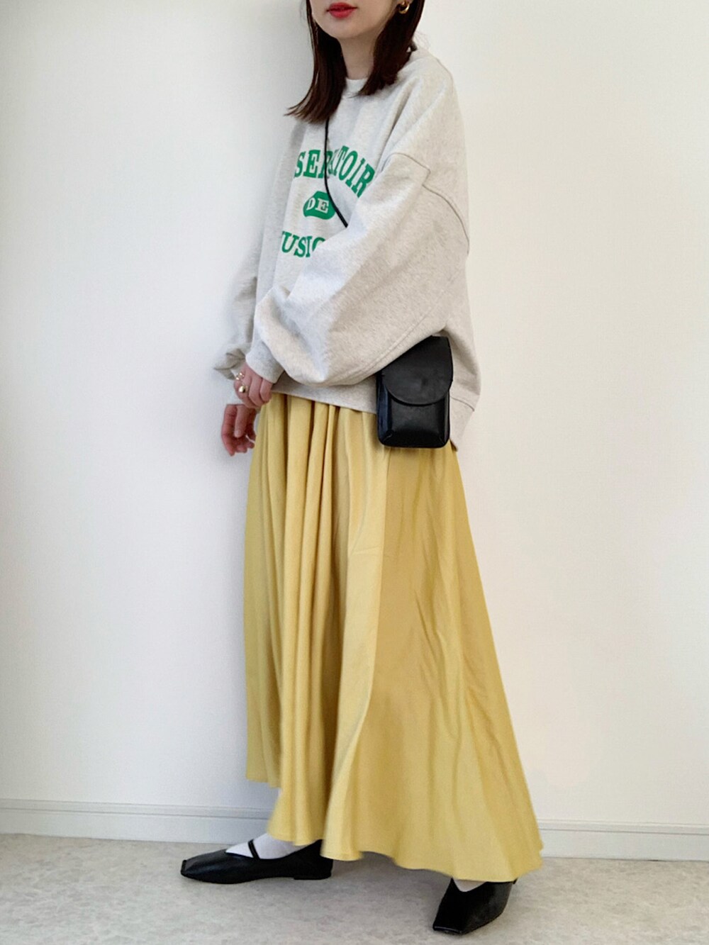 ホワイト系のニット/セーター、イエロー系のスカート、ブラック系のパンプスを着用したレディースの冬コーディネートの2枚目の写真
