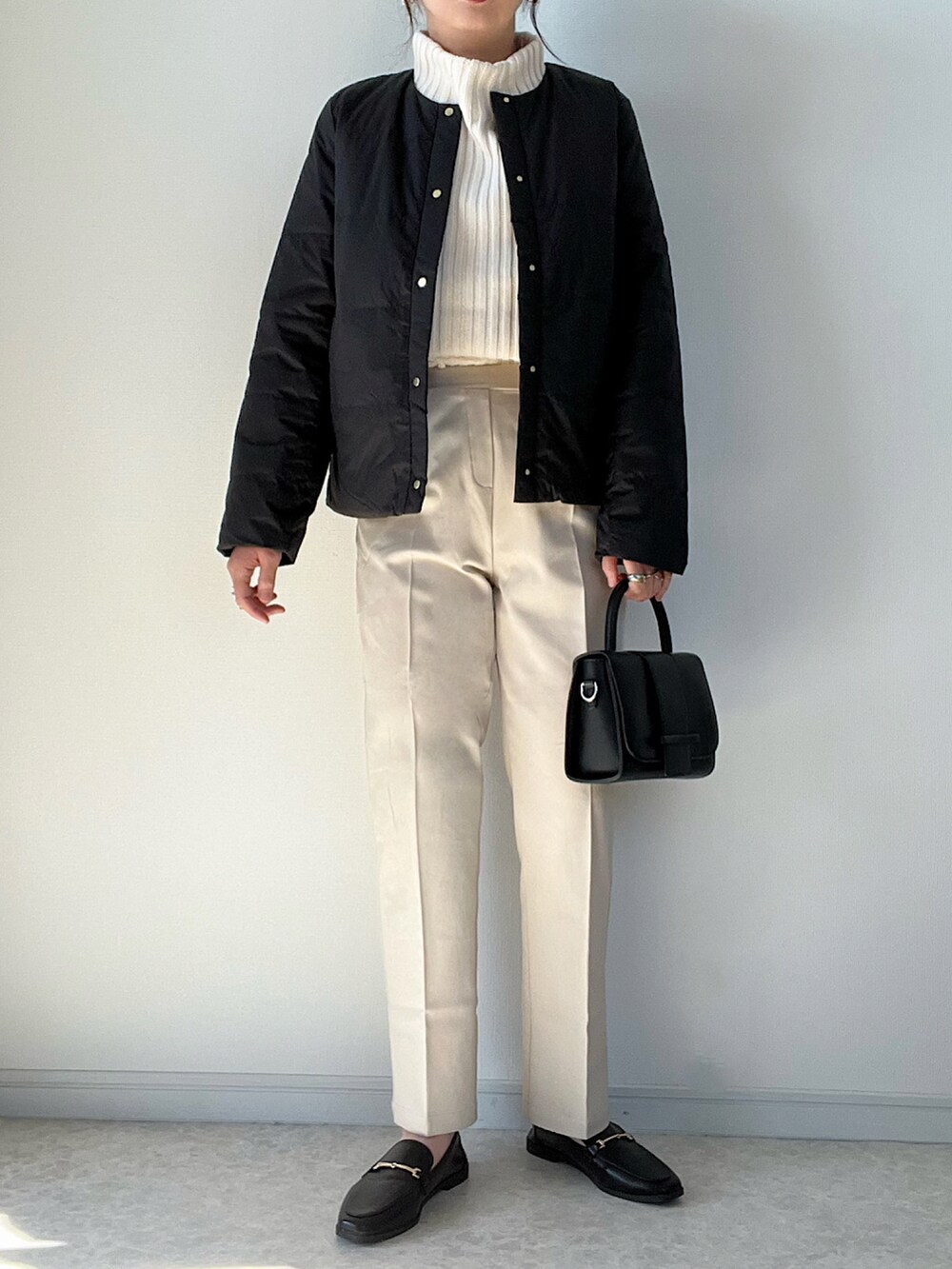 ホワイト系のニット/セーター、ホワイト系のスラックス、ブラウン系のパンプスを着用したレディースの秋コーディネートの3枚目の写真