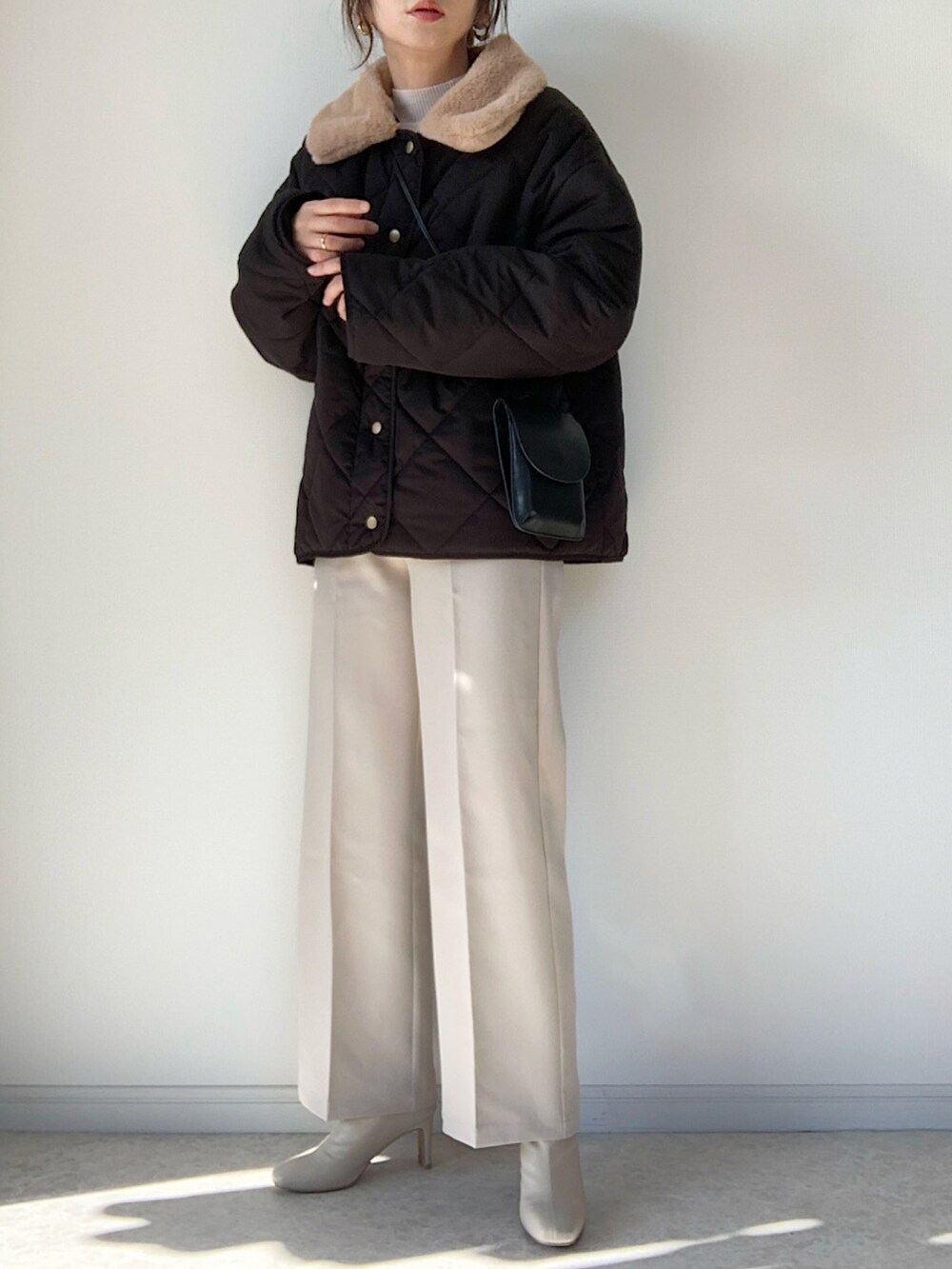 ブラック系のダウンジャケット/コート、ベージュ系のスラックス、ベージュ系のブーツを着用したレディースの冬コーディネートの2枚目の写真