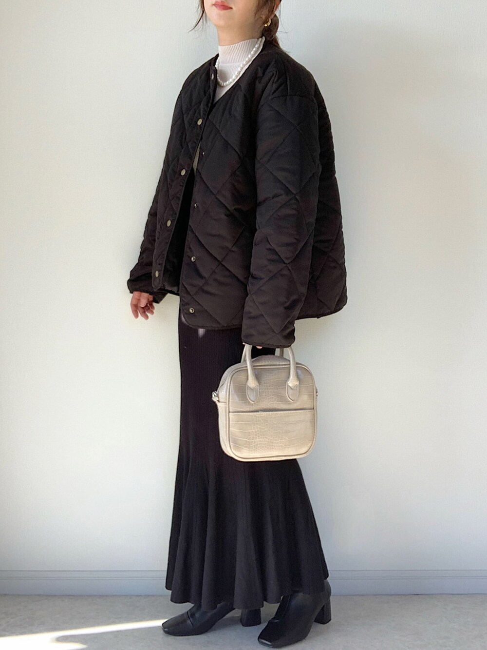 ブラック系のダウンジャケット/コート、ホワイト系のTシャツ/カットソー、ブラック系のショルダーバッグを着用したレディースの冬コーディネートの3枚目の写真