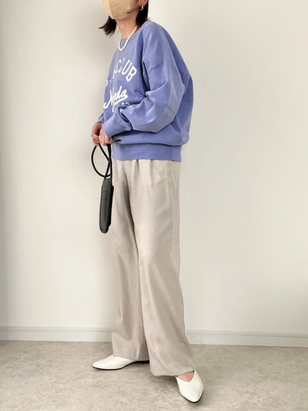 パープル系のスウェット、ブラック系のショルダーバッグ、ブルー系のデニムパンツを着用したレディースの冬コーディネートの2枚目の写真