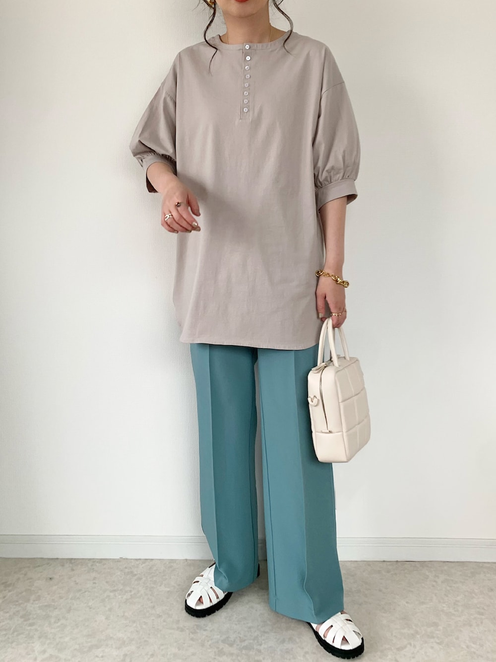 ホワイト系のショルダーバッグ、ホワイト系のサンダル、ベージュ系のTシャツ/カットソーを着用したレディースの春コーディネートの2枚目の写真