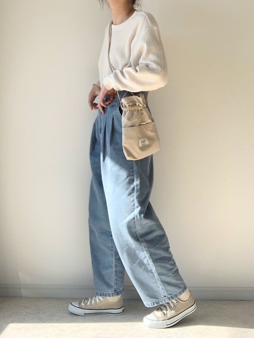 ホワイト系のTシャツ/カットソー、ブルー系のデニムパンツ、ベージュ系のスニーカーを着用したレディースの冬コーディネートの2枚目の写真