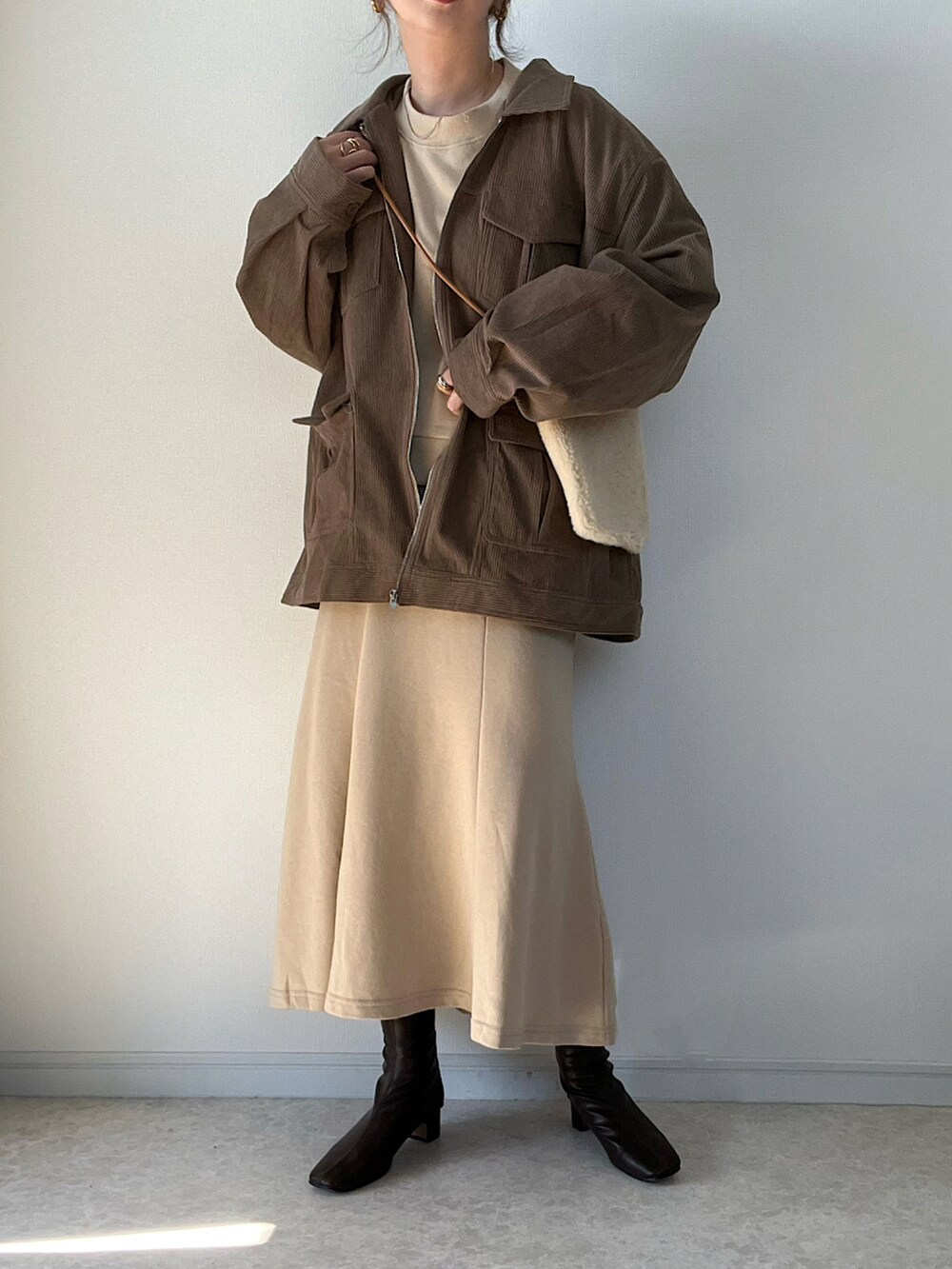 ブラウン系のブルゾン、ホワイト系のTシャツ/カットソー、ホワイト系のショルダーバッグを着用したレディースの秋コーディネートの2枚目の写真