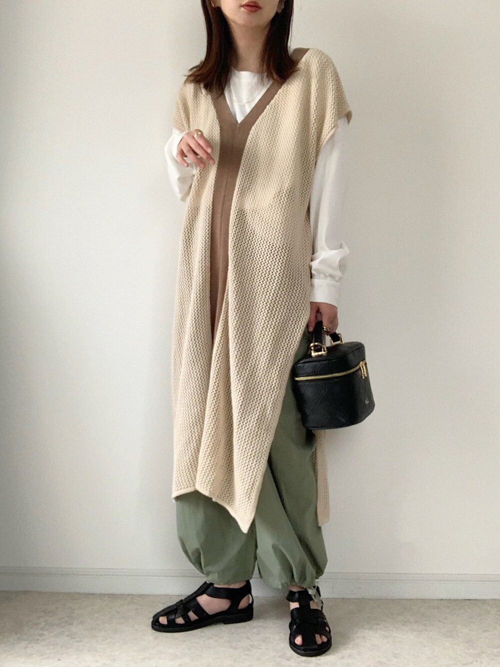 ブラック系のショルダーバッグ、ベージュ系のワンピース/ドレス、ホワイト系のTシャツ/カットソーを着用したレディースの春コーディネートの3枚目の写真