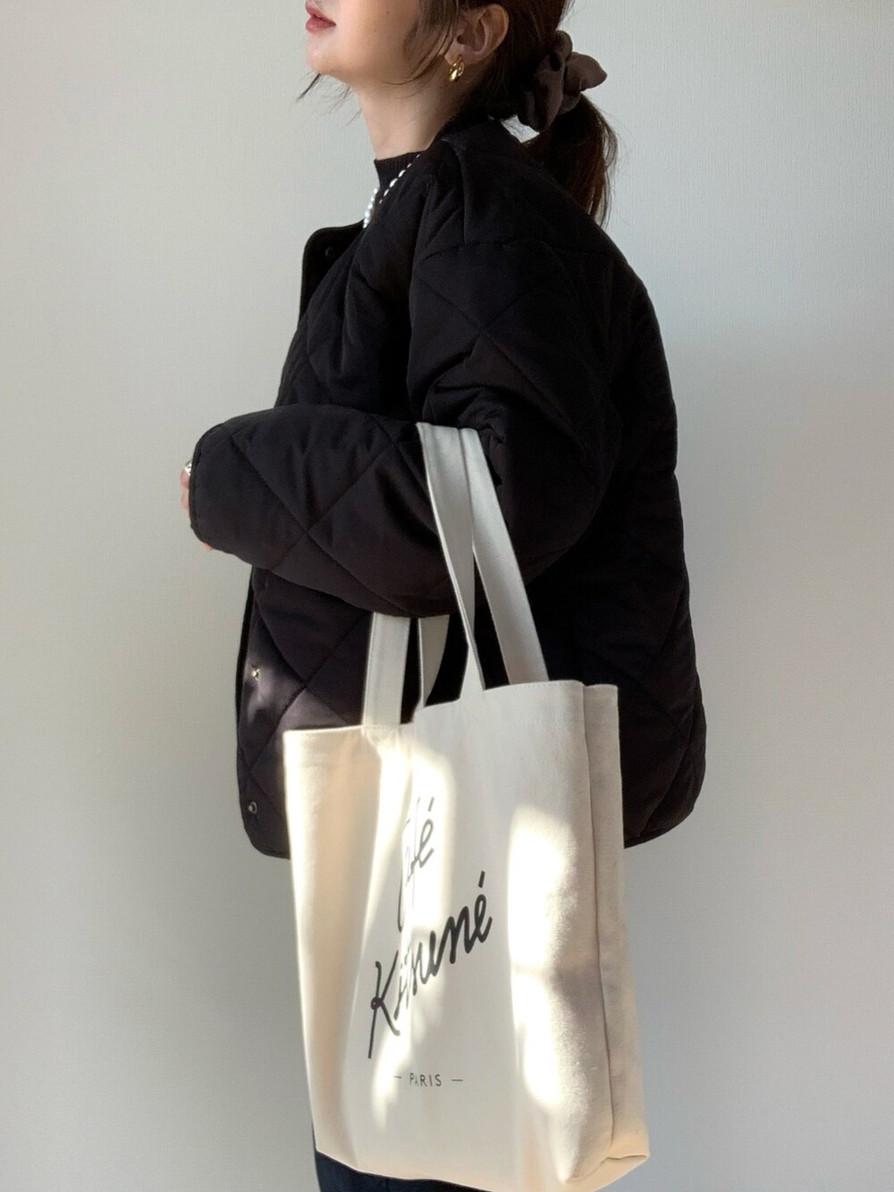 ブラック系のダウンジャケット/コート、ホワイト系のトートバッグ、ブルー系のデニムパンツを着用したレディースの冬コーディネートの2枚目の写真