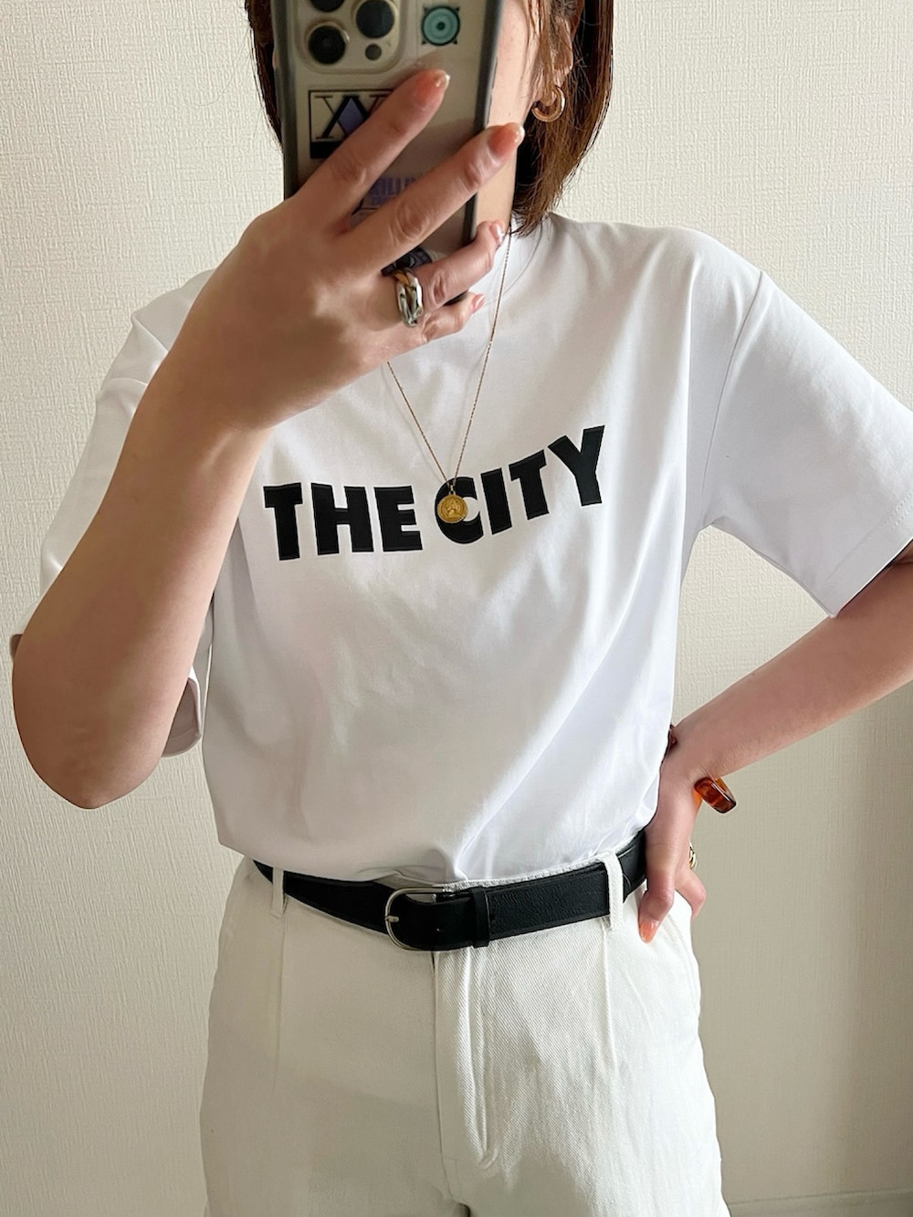 ホワイト系のTシャツ/カットソー、ブラック系のパンツ、ブラック系のショルダーバッグを着用したレディースの春コーディネートの2枚目の写真