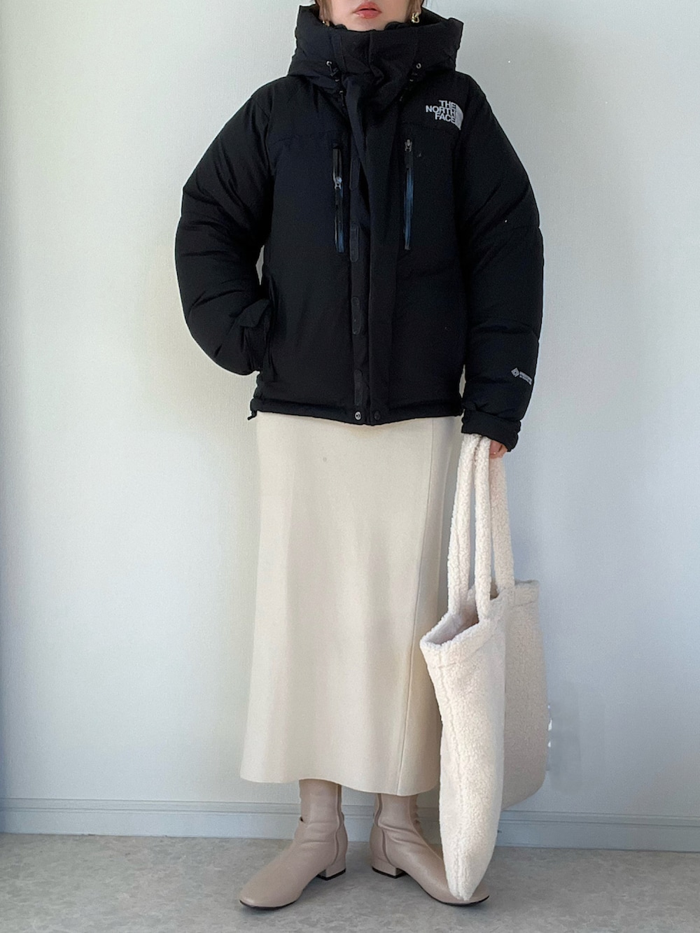 ブラック系のダウンジャケット/コート、ホワイト系のワンピース、ブラック系のショルダーバッグを着用したレディースの冬コーディネートの2枚目の写真