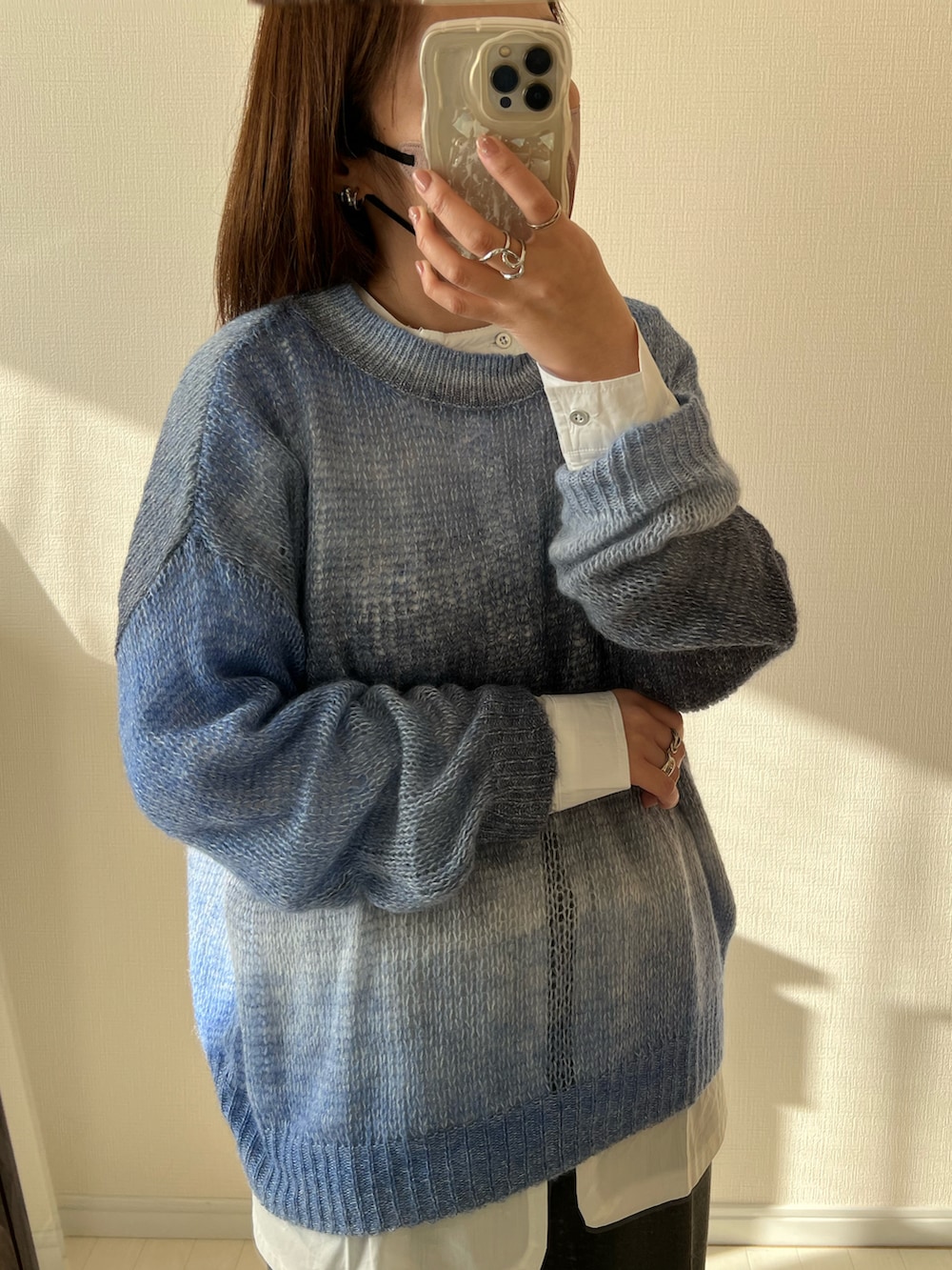 ブルー系のニット/セーター、ホワイト系のシャツ/ブラウス、ブラック系のショルダーバッグを着用したレディースの冬コーディネートの2枚目の写真