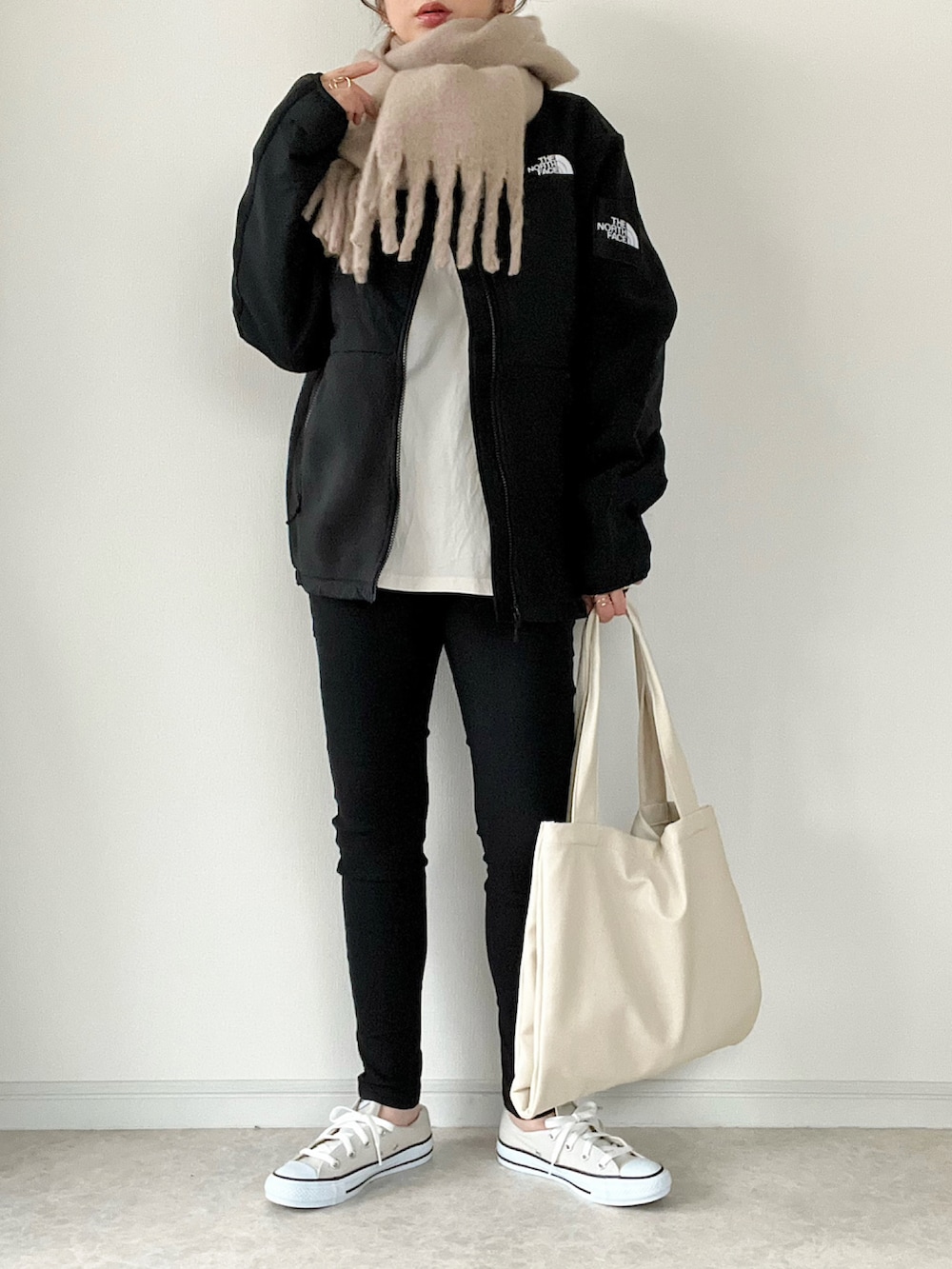 ブラック系のその他アウター、ホワイト系のTシャツ/カットソー、ホワイト系のトートバッグを着用したレディースの冬コーディネートの2枚目の写真