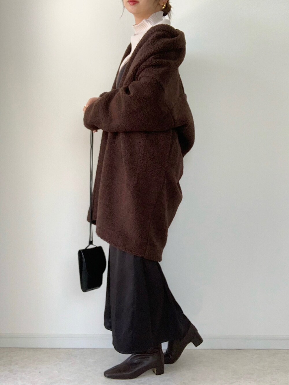 ホワイト系のニット/セーター、ブラウン系のブーツ、ブラウン系のノーカラーコートを着用したレディースの秋コーディネートの3枚目の写真