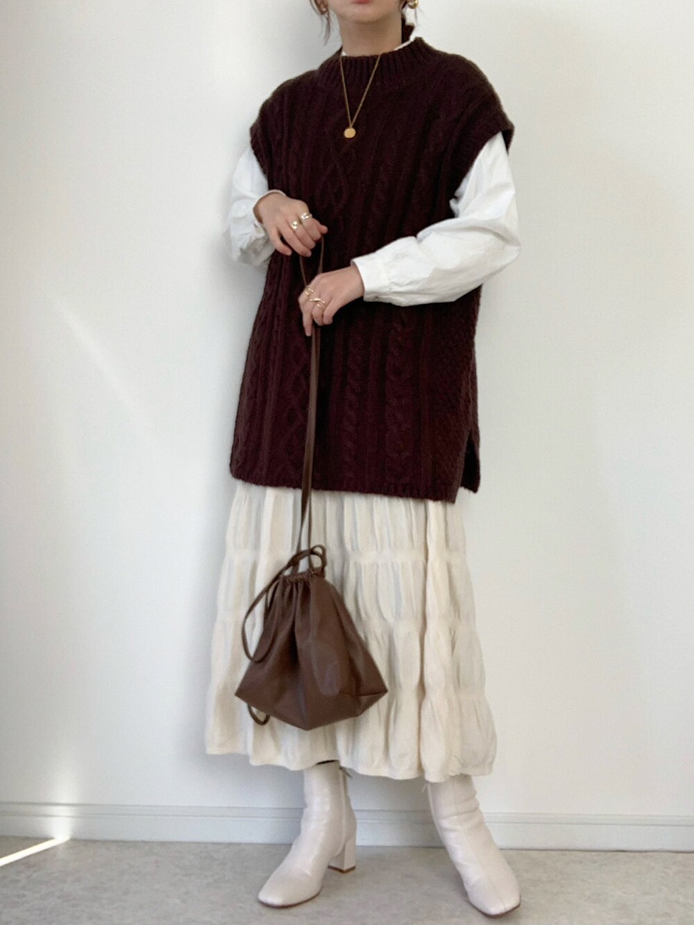 ブラウン系のベスト、ベージュ系のブーツ、ブラウン系のチェスターコートを着用したレディースの冬コーディネートの2枚目の写真