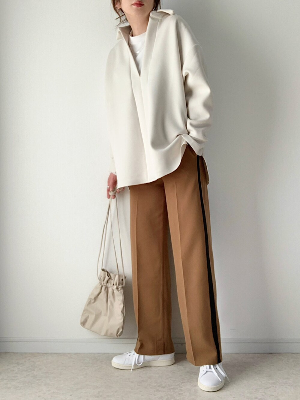 ホワイト系のシャツ/ブラウス、ベージュ系のスラックス、ホワイト系のブーツを着用したレディースの冬コーディネートの2枚目の写真