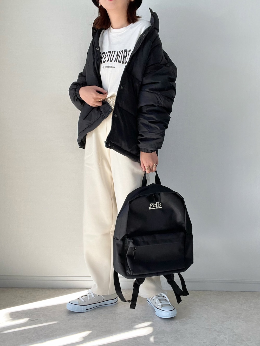 ブラック系のダウンジャケット/コート、ホワイト系のTシャツ/カットソー、ブラック系のブーツを着用したレディースの秋コーディネートの3枚目の写真