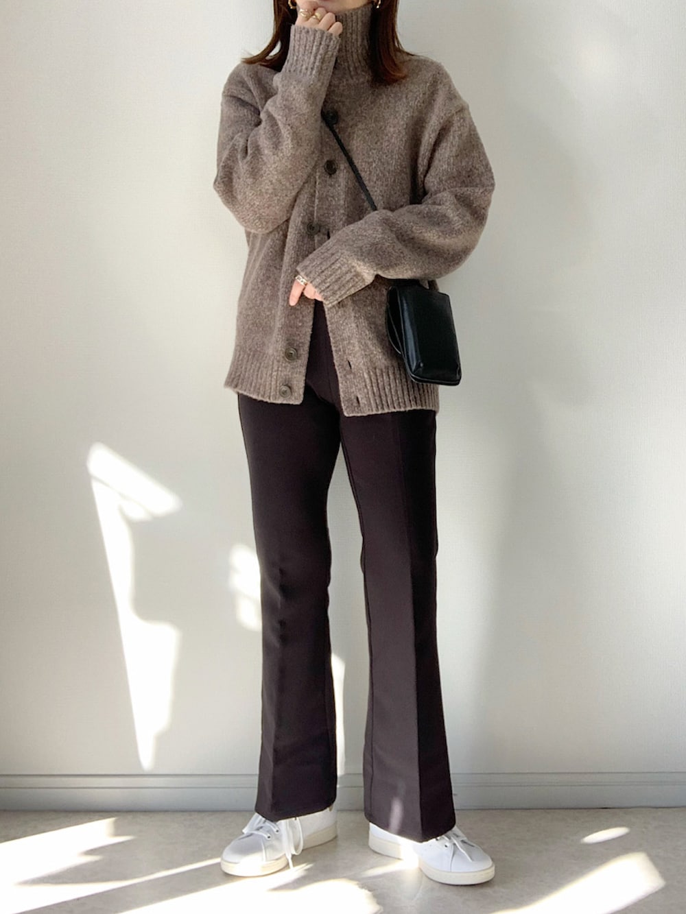 ブラウン系のカーディガン/ボレロ、ホワイト系のスニーカー、ブラック系のボディバッグ/ウエストポーチを着用したレディースの冬コーディネートの2枚目の写真