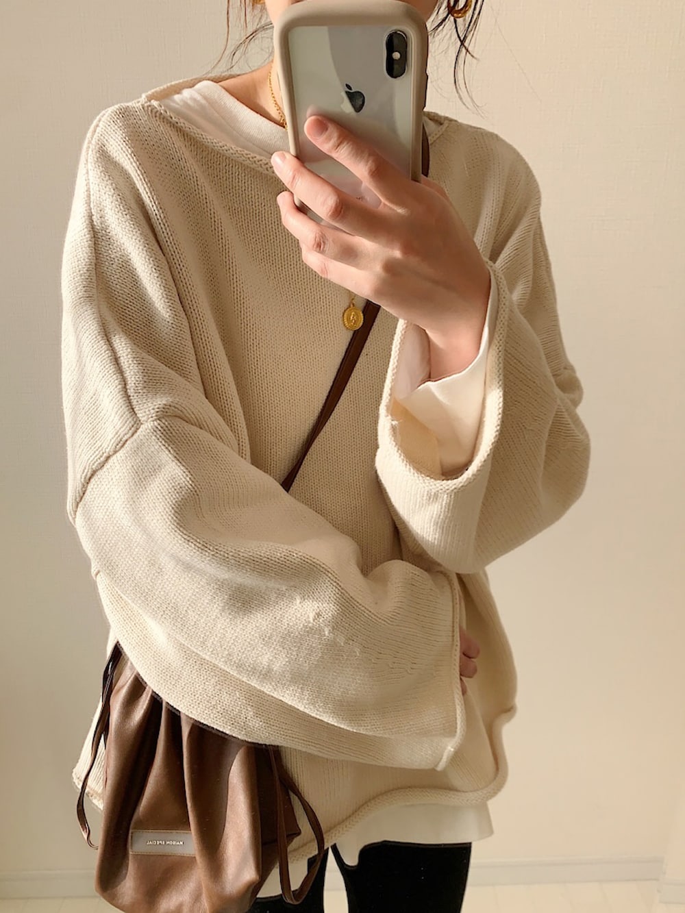 ホワイト系のニット/セーター、ホワイト系のTシャツ/カットソー、ホワイト系のスニーカーを着用したレディースの冬コーディネートの2枚目の写真