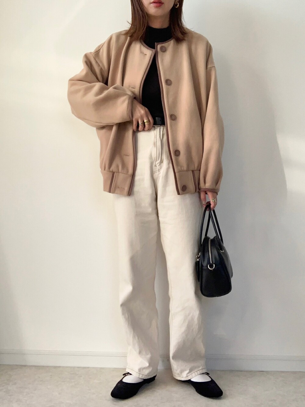 ベージュ系のカーディガン/ボレロ、ブラック系のTシャツ/カットソー、ホワイト系のデニムパンツを着用したレディースの秋コーディネートの2枚目の写真