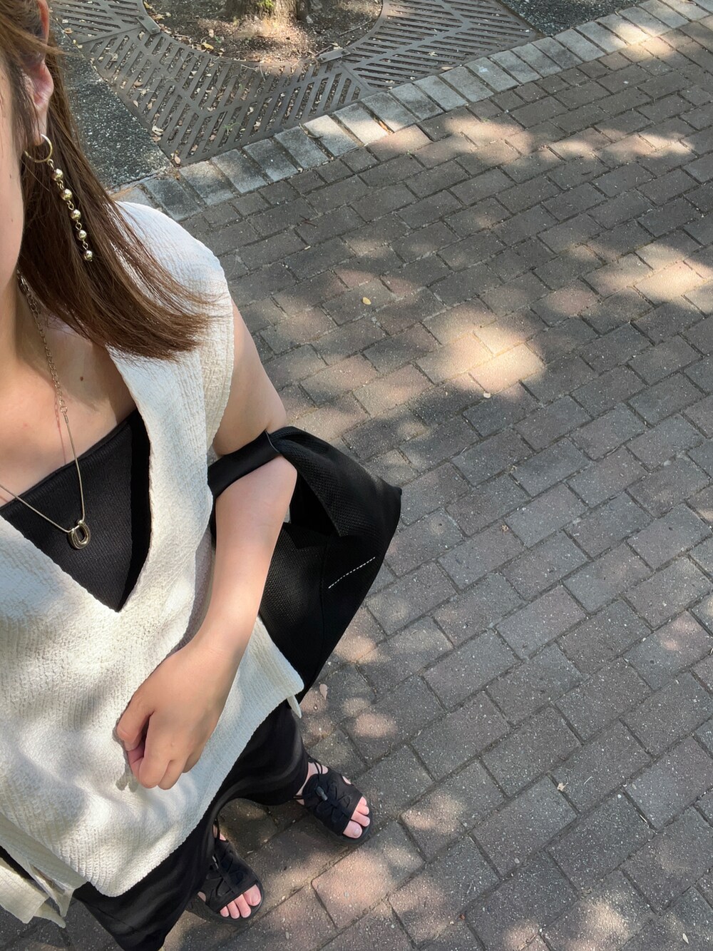 ブラック系のワンピース、ホワイト系のベスト、ブラック系のトートバッグを着用したレディースの夏コーディネートの2枚目の写真