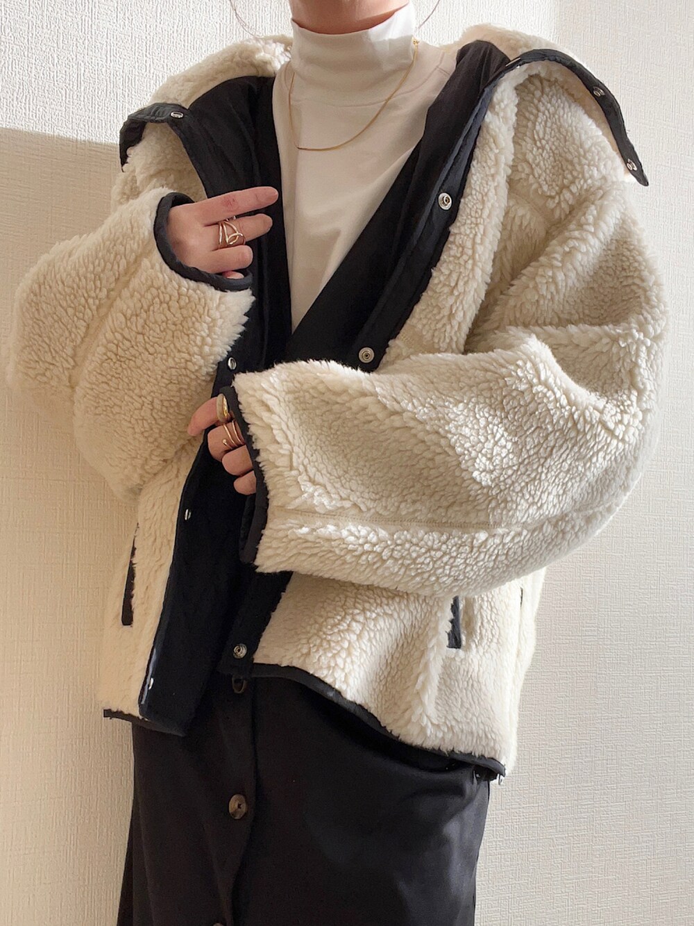 ホワイト系のブルゾン、ブラック系のサロペット/オーバーオール、ブラック系のブーツを着用したレディースの冬コーディネートの2枚目の写真