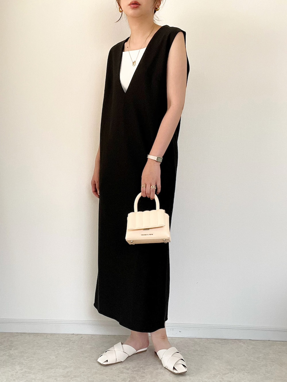 ホワイト系のシャツ/ブラウス、ブラック系のジャンパースカート、ベージュ系のハンドバッグを着用したレディースの夏コーディネートの2枚目の写真