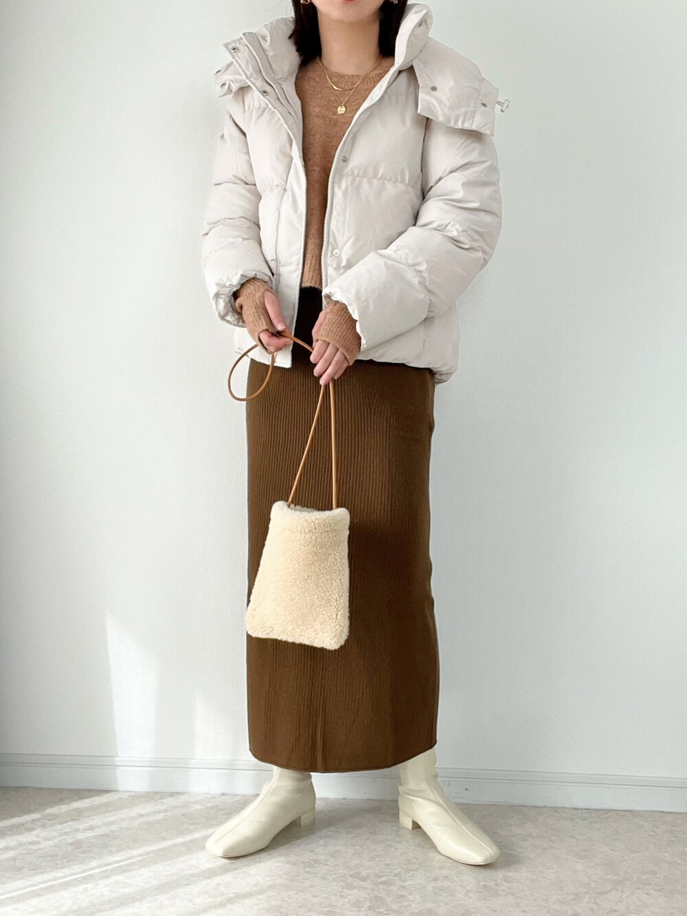 オレンジ系のニット/セーター、ブラウン系のスカート、ホワイト系のブーツを着用したレディースの秋コーディネートの2枚目の写真