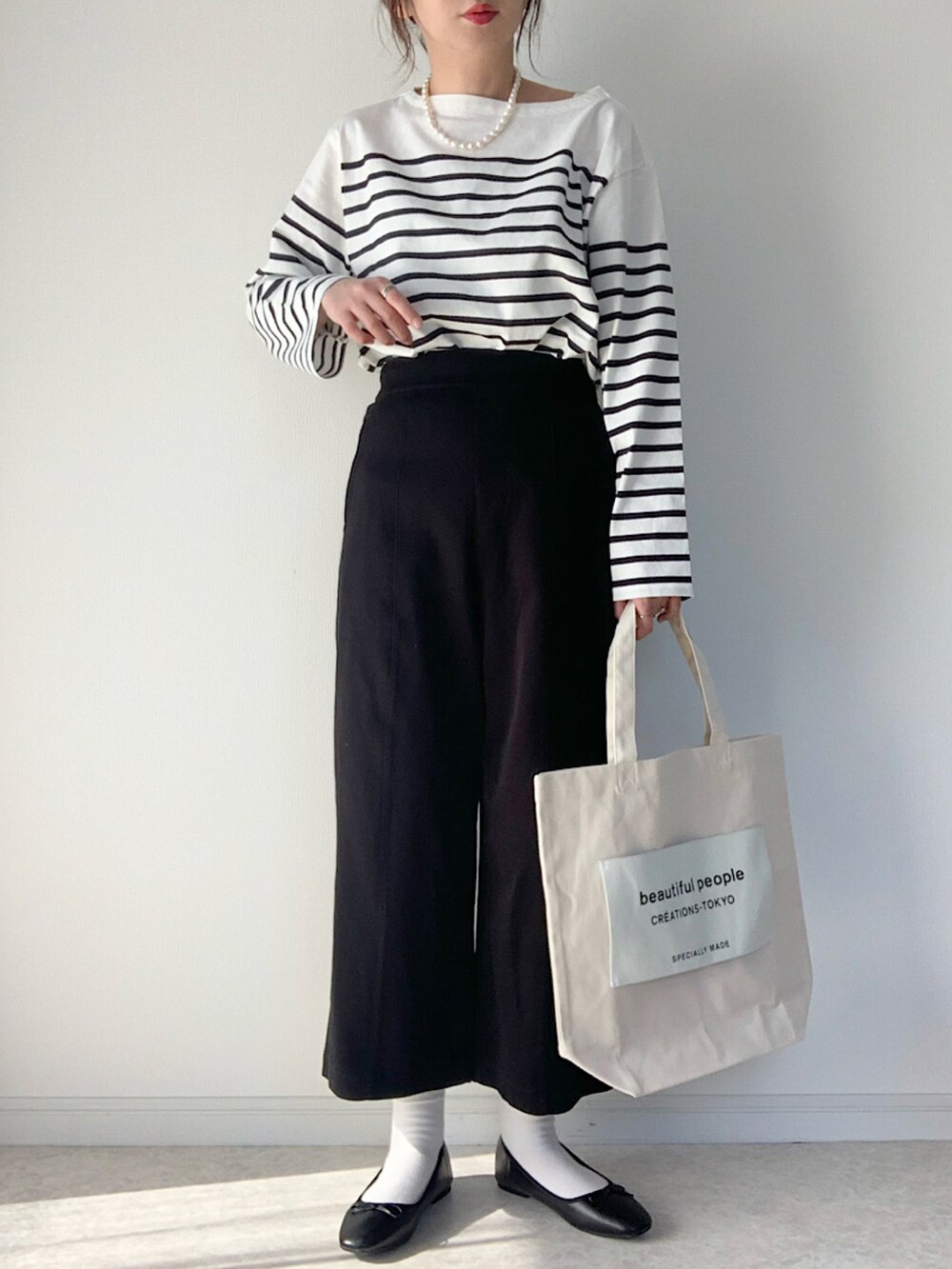 ホワイト系のトートバッグ、ブラック系のバレエシューズ、ホワイト系のTシャツ/カットソーを着用したレディースの冬コーディネートの2枚目の写真