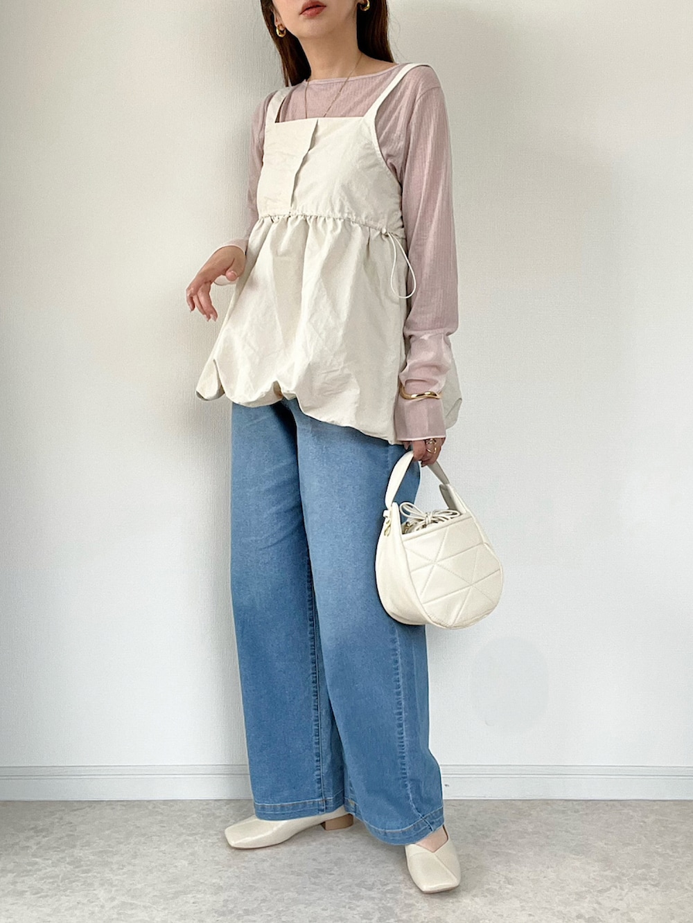 ベージュ系のTシャツ/カットソー、ブルー系のデニムパンツ、ホワイト系のショルダーバッグを着用したレディースの春コーディネートの2枚目の写真