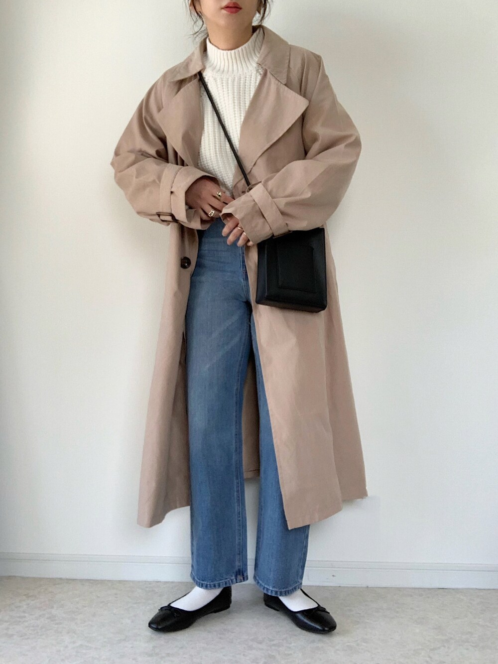 ホワイト系のニット/セーター、ブラック系のショルダーバッグ、ベージュ系のトレンチコートを着用したレディースの冬コーディネートの2枚目の写真