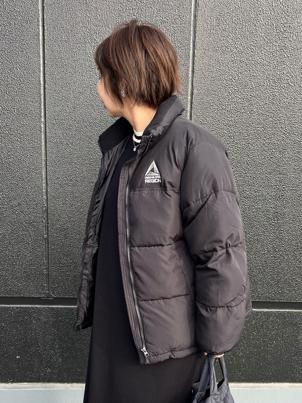 ブラック系のダウンジャケット/コート、ブラック系のワンピース、ブラック系のショルダーバッグを着用したレディースの冬コーディネートの2枚目の写真