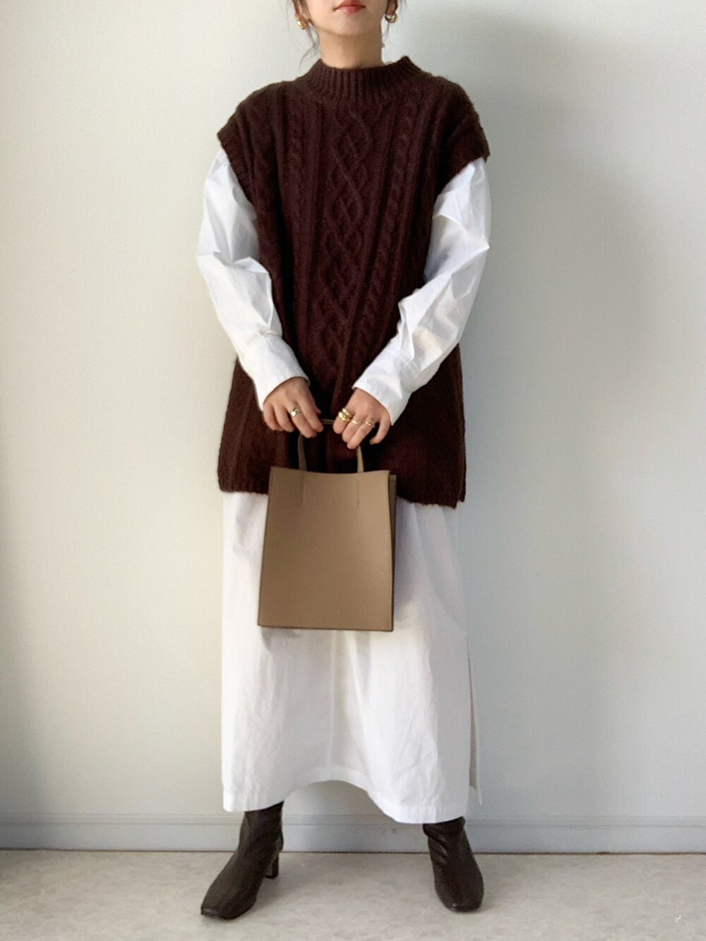 ブラック系のダウンジャケット/コート、ブラウン系のベスト、ブラウン系のブーツを着用したレディースの冬コーディネートの2枚目の写真