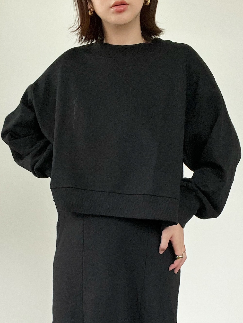 ブラック系のスウェット、ブラック系のスカート、グレー系のベストを着用したレディースの冬コーディネートの3枚目の写真