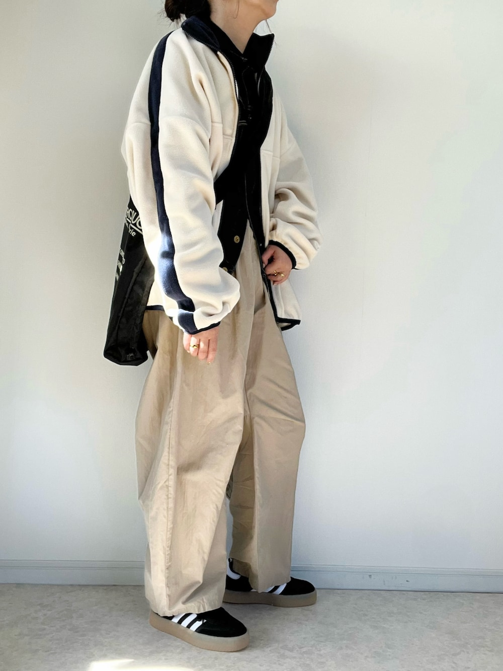 ブラック系のショルダーバッグ、ベージュ系のチノパンツ、ブラック系のスニーカーを着用したレディースの冬コーディネートの2枚目の写真