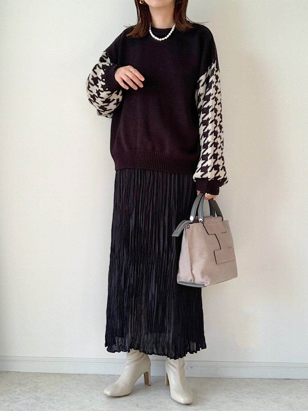 ブラック系のニット/セーター、ホワイト系のデニムパンツ、ホワイト系のスニーカーを着用したレディースの冬コーディネートの3枚目の写真